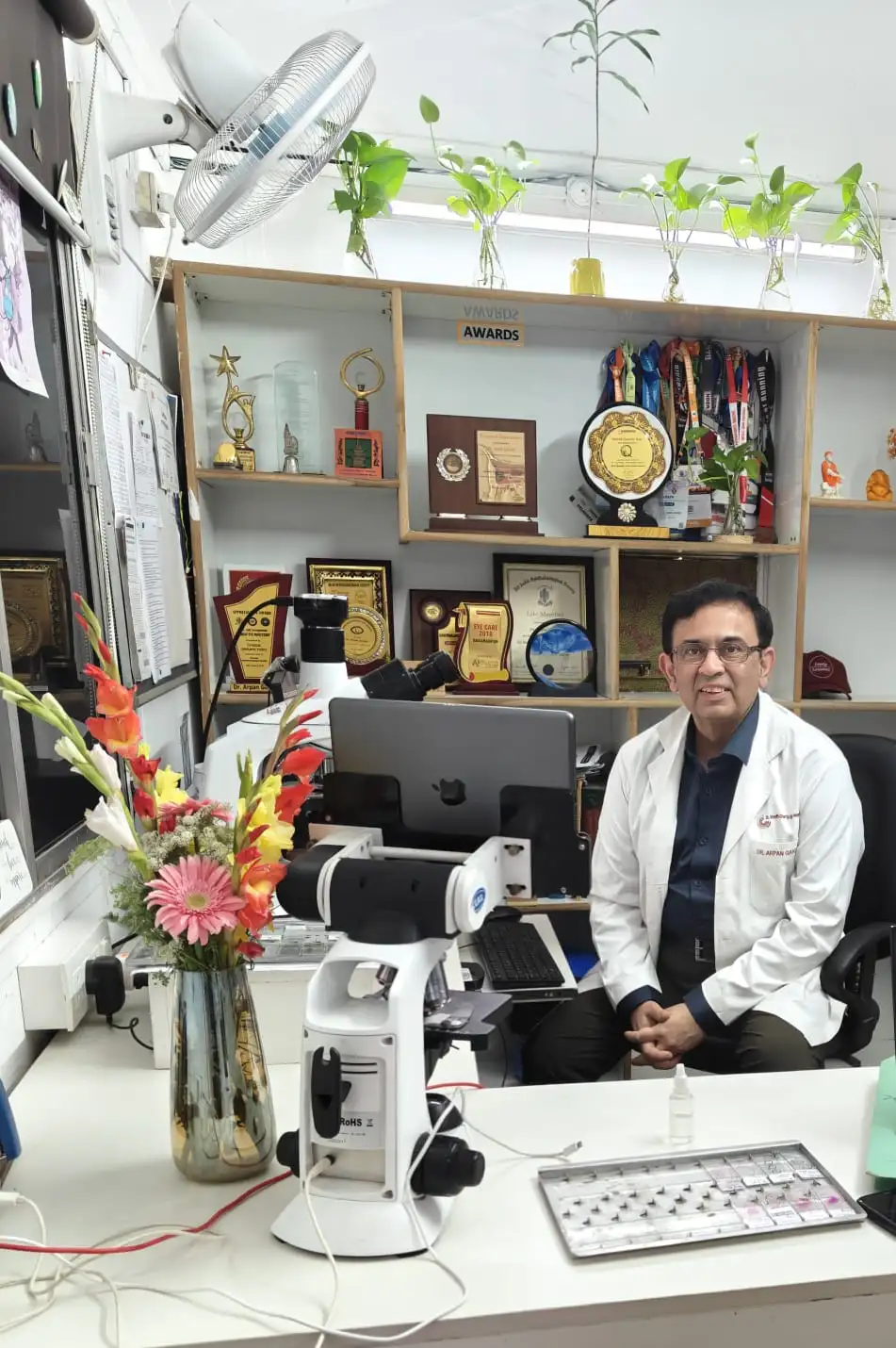 Dr. Arpan Gandhi at his office with awards and microscope